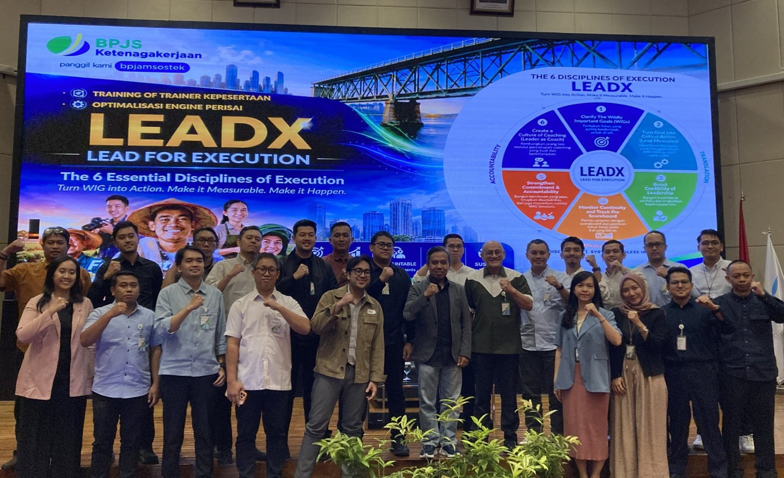 LEADX program participants posing in front of the 6 Disciplines of Execution presentation screen